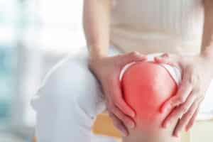 A person holding their red, inflamed knee