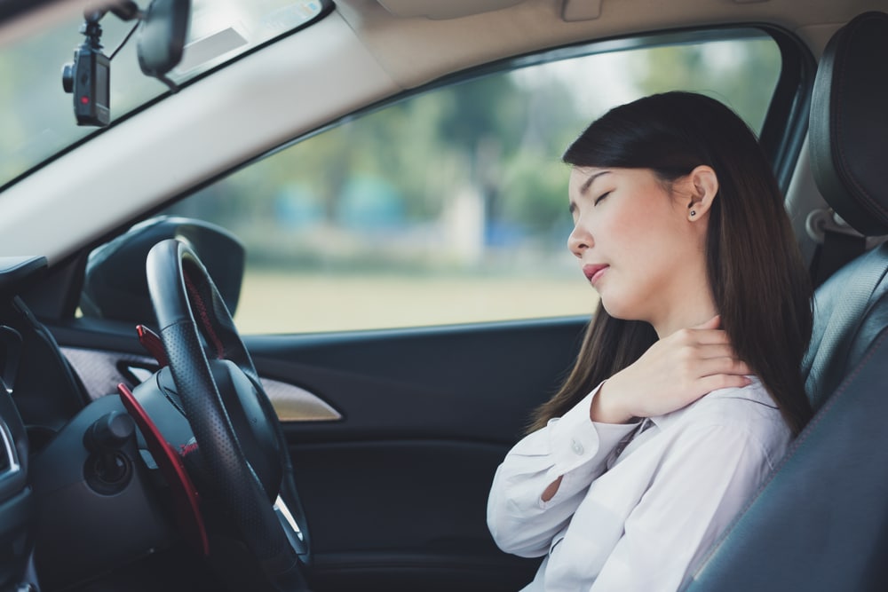 Woman in car suffering from chronic neck pain